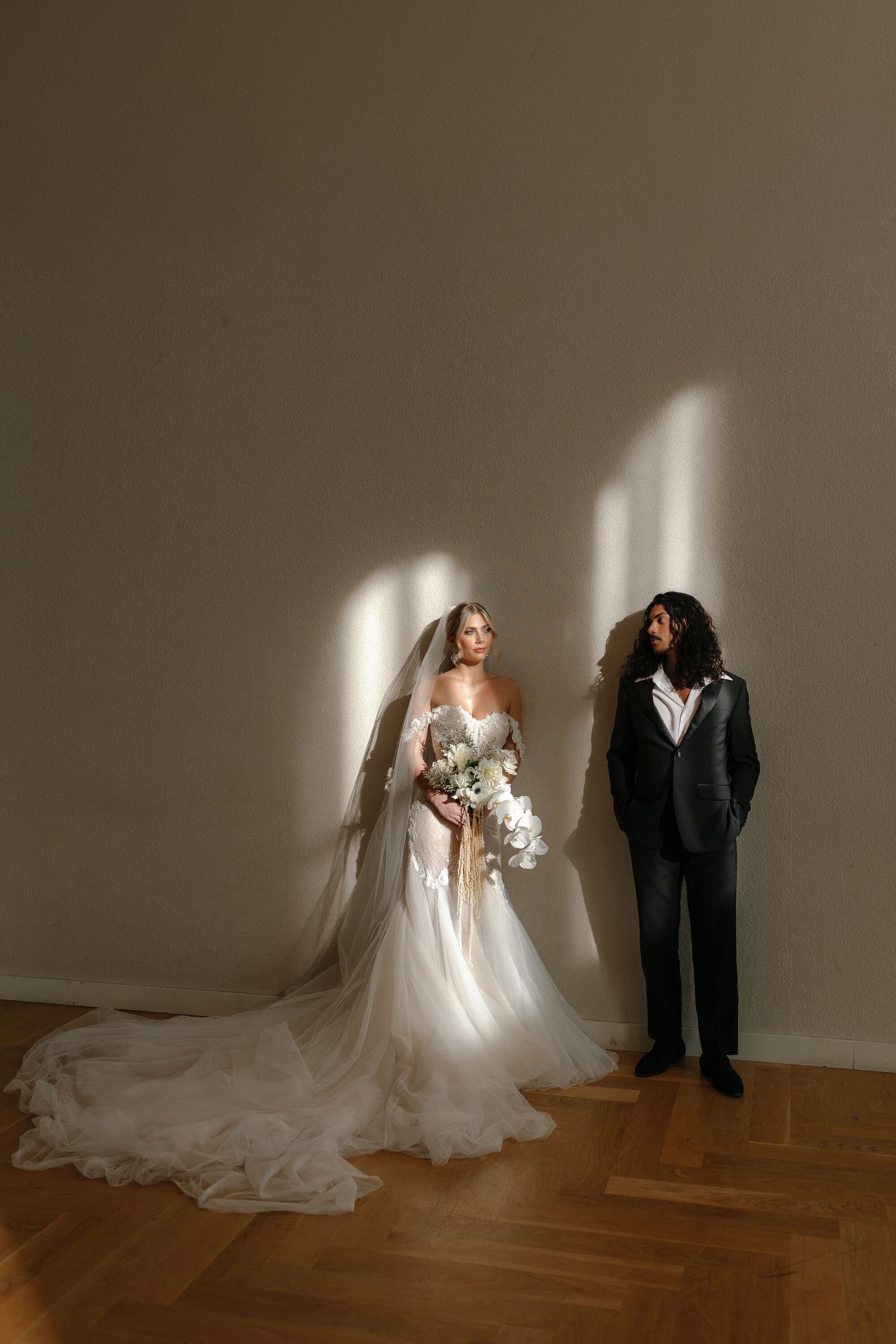 Editorial wedding portrait of a bride in a flowing veil and groom in soft window light, photographed by Colorado wedding photographer Sabra Photo