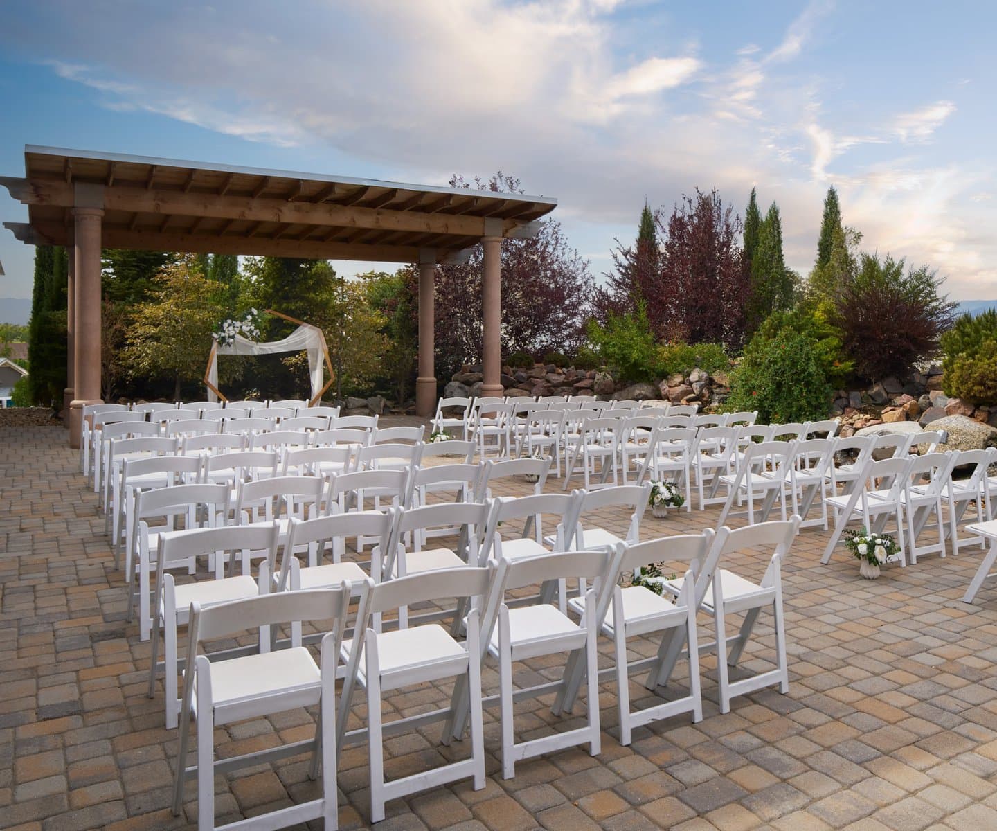 Outdoor wedding ceremony site with a wooden pergola and white chairs at Briarhurst Manor in Manitou Springs, Colorado