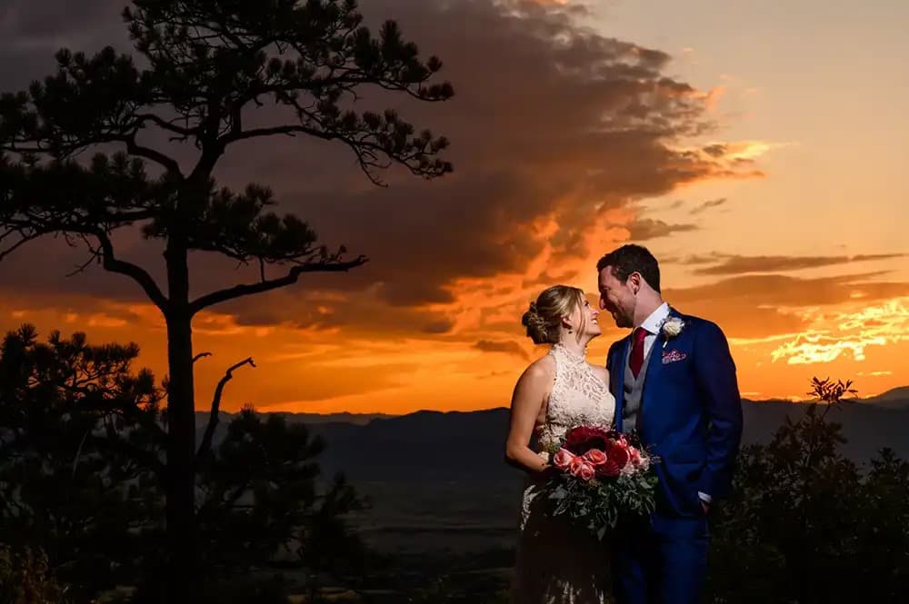 Bride and groom at a fiery Colorado sunset overlooking the valley at Cherokee Ranch & Castle in Sedalia, Colorado