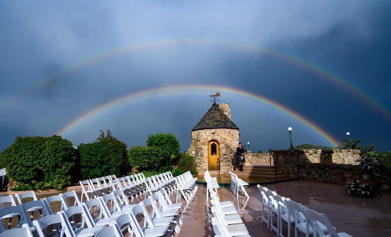 Double rainbow arcing over the stone castle ceremony site with a bagpiper at Cherokee Ranch & Castle in Sedalia, Colorado