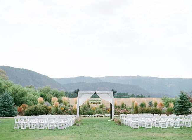 Outdoor wedding ceremony with a draped arch and sweeping mountain views at Crooked Willow Farms in Larkspur, Colorado