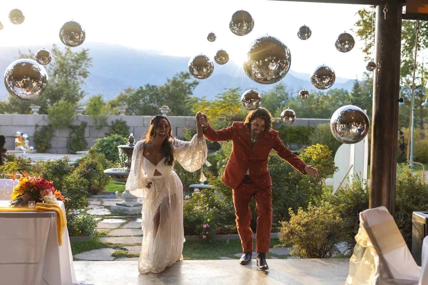 Newlyweds making their grand entrance under disco balls with mountain views at Hillside Gardens & Event Center near Monument, Colorado