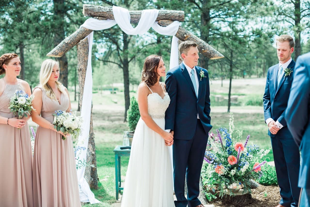 Couple at their forest wedding ceremony surrounded by ponderosa pines at The Lodge at Cathedral Pines in Black Forest, Colorado