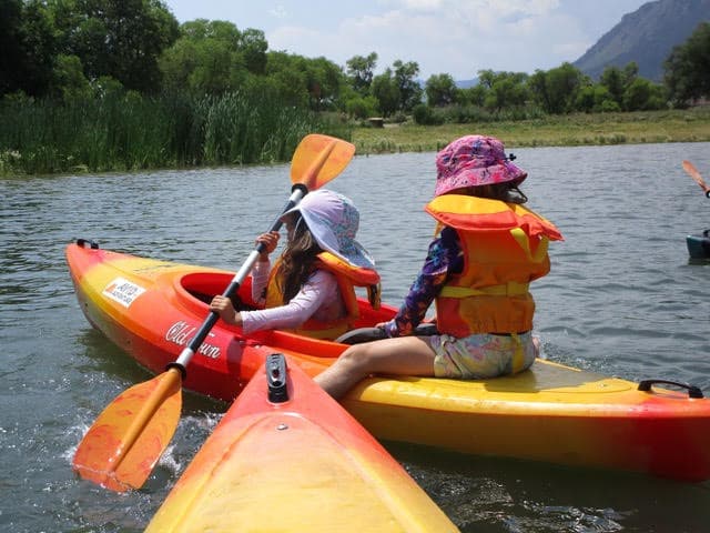 Kayakers paddling on the spring-fed lake with mountain views at the Palmer Lake Recreation Area in Palmer Lake, Colorado
