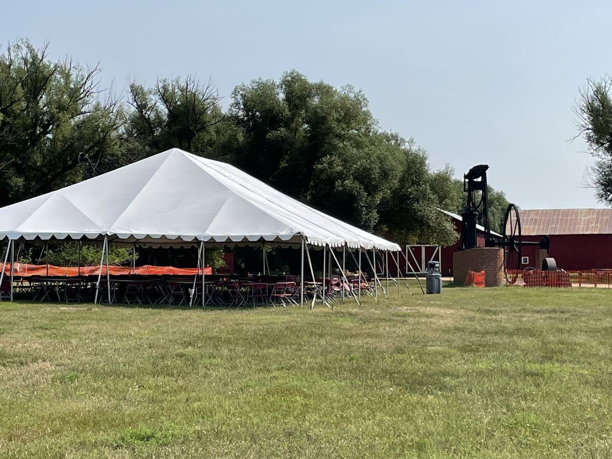 White event tent beside the historic red hay barn at Reynolds Ranch in Monument, Colorado