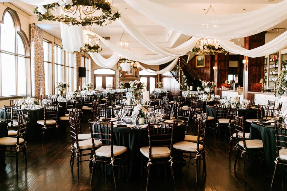 Elegant reception hall with draped ceiling, greenery, and chandeliers at The Pinery at the Hill in Colorado Springs, Colorado